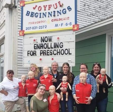A group of people standing in front of a sign that says joyful beginnings