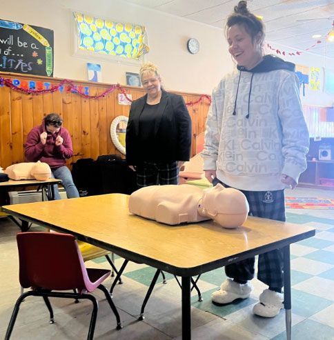 A woman is standing in front of a table with a mannequin on it.
