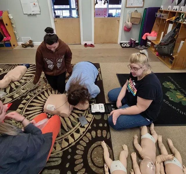 A group of people are sitting on the floor with dolls
