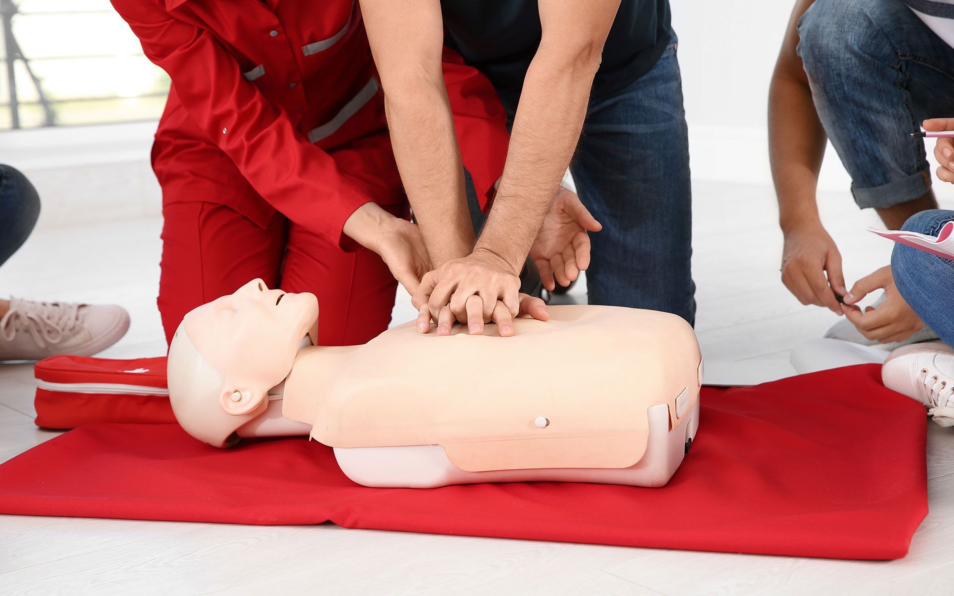 A group of people are practicing first aid on a mannequin.