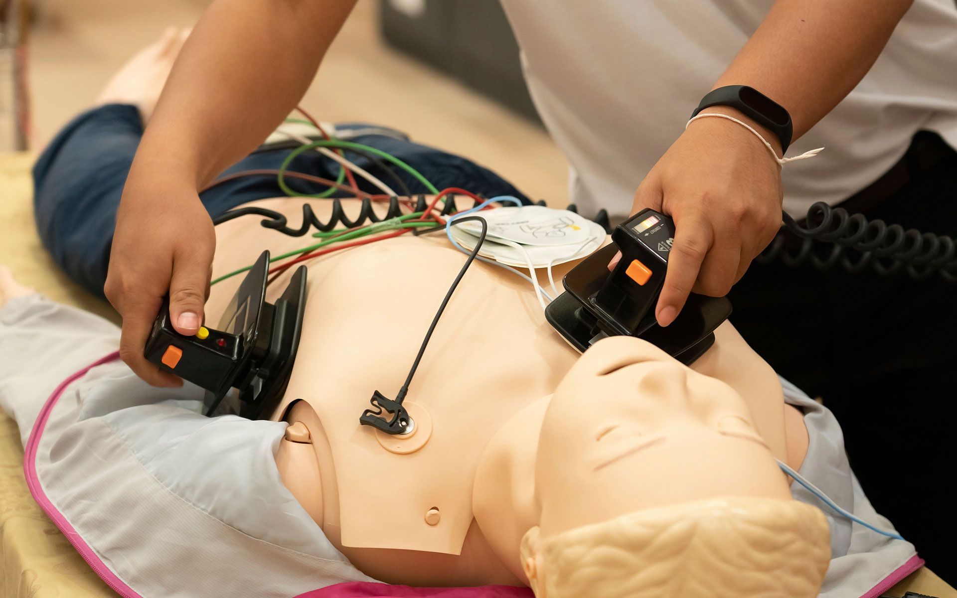 A person is using a defibrillator on a mannequin.