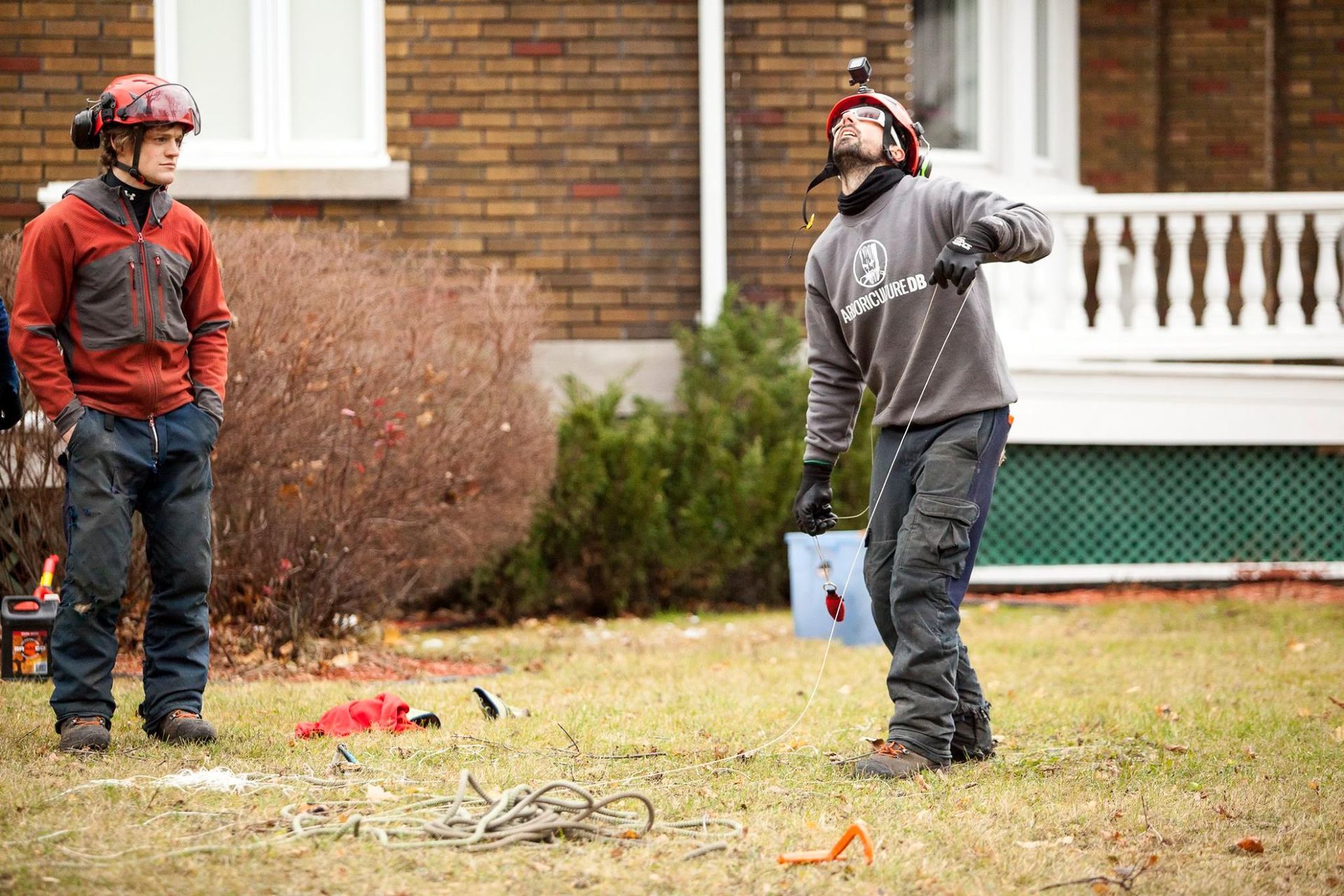 Deux hommes se tiennent dans une cour devant une maison en briques.