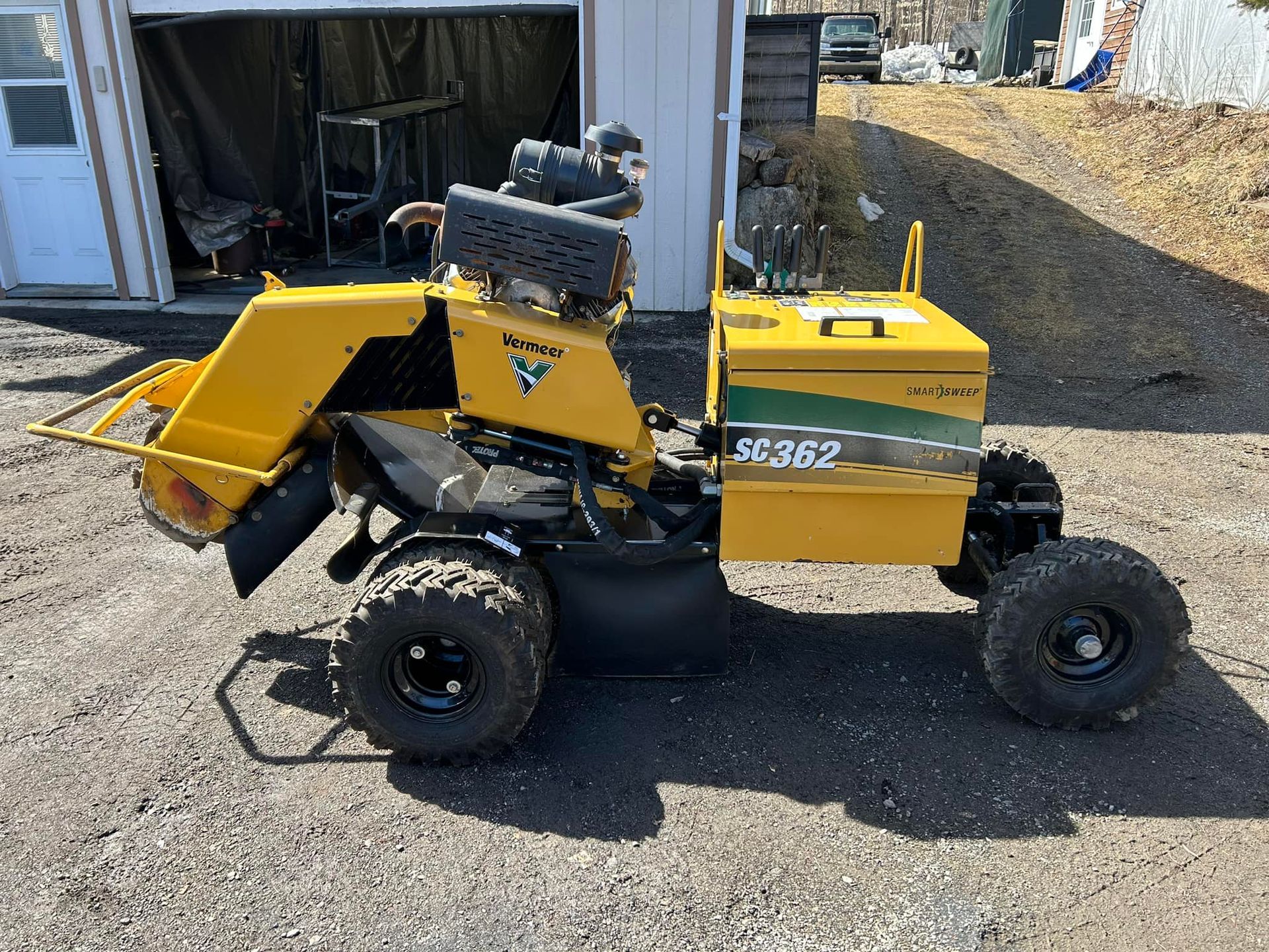 Un tracteur jaune est garé devant un garage.