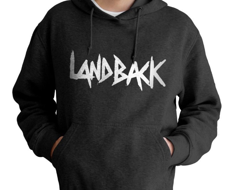 A person wearing a black landback hoodie with their hands in their pockets