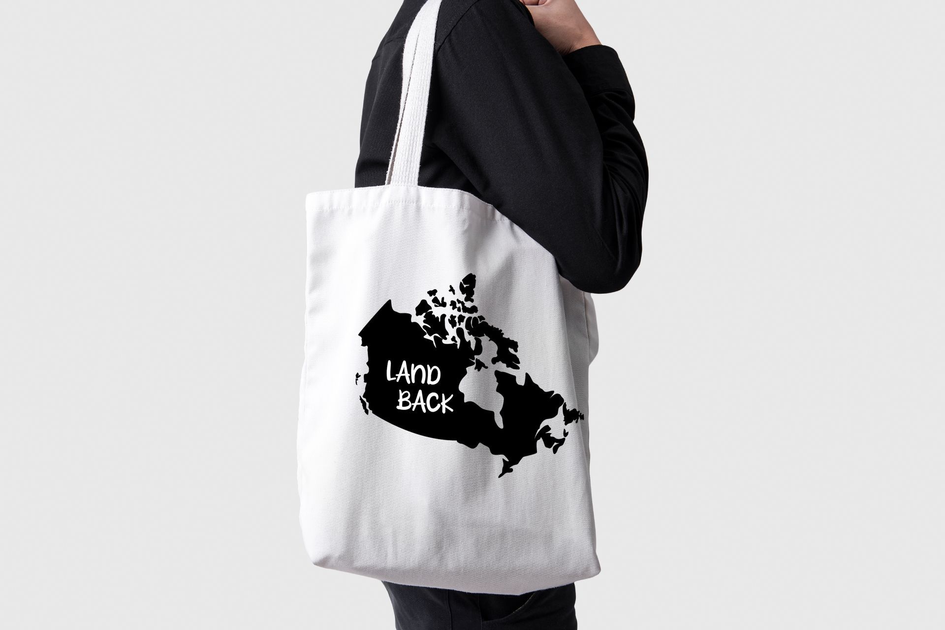 A person is holding a white tote bag with a map of canada on it.
