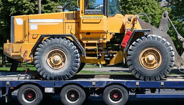 A yellow bulldozer is sitting on top of a blue trailer.