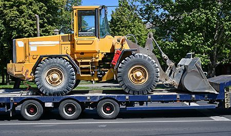 A yellow bulldozer is sitting on top of a blue trailer.