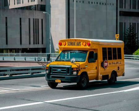 A yellow school bus is driving down a city street.