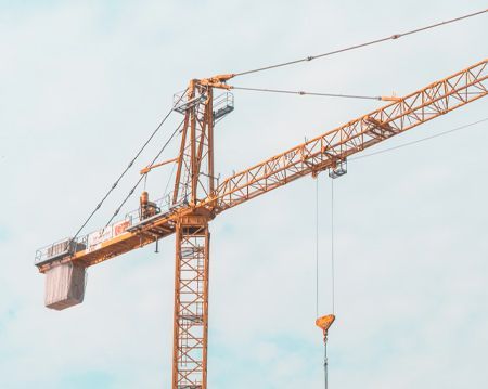 A large yellow construction crane is against a blue sky.