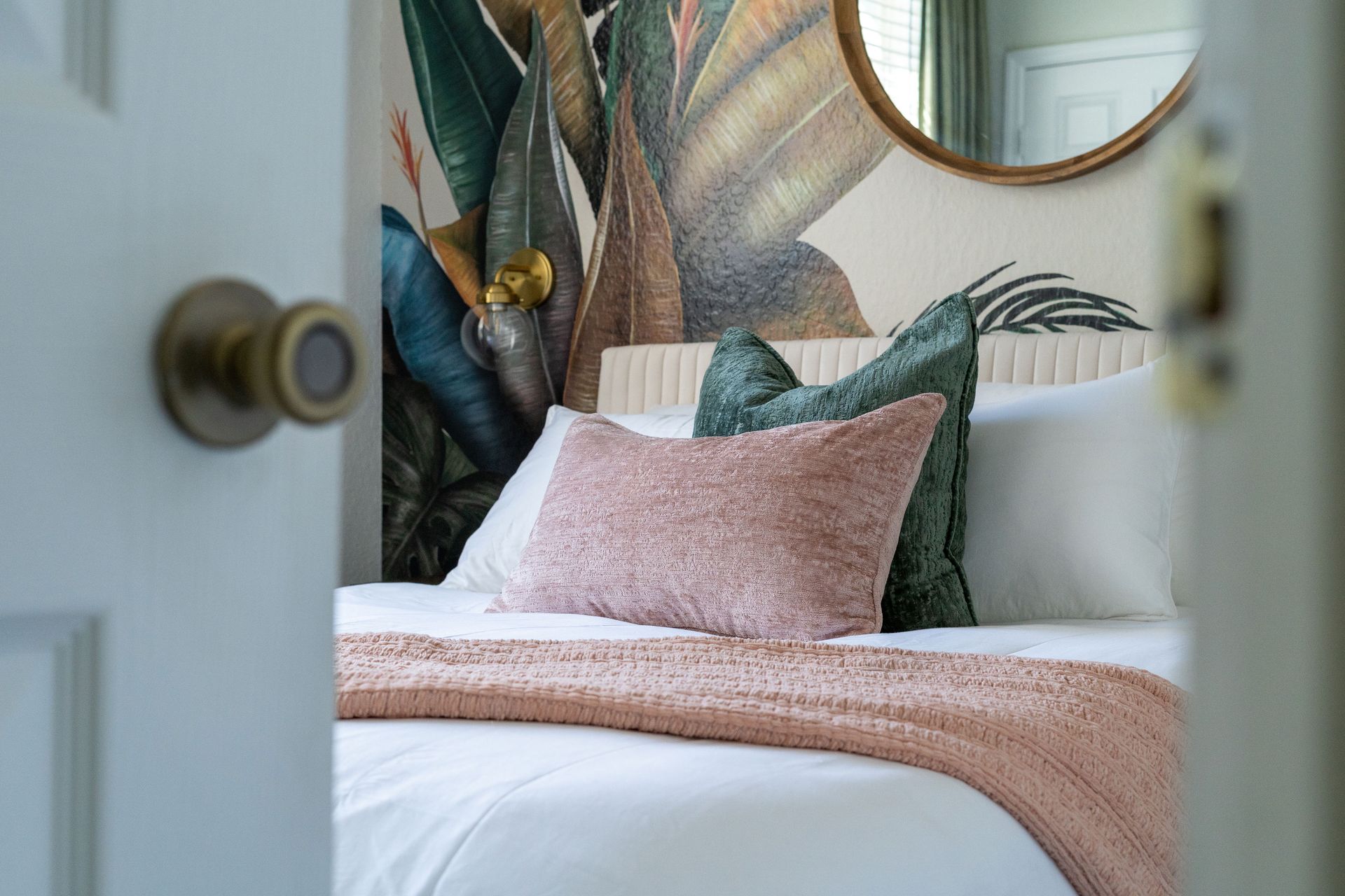 A bedroom with a bed , mirror and painting on the wall.