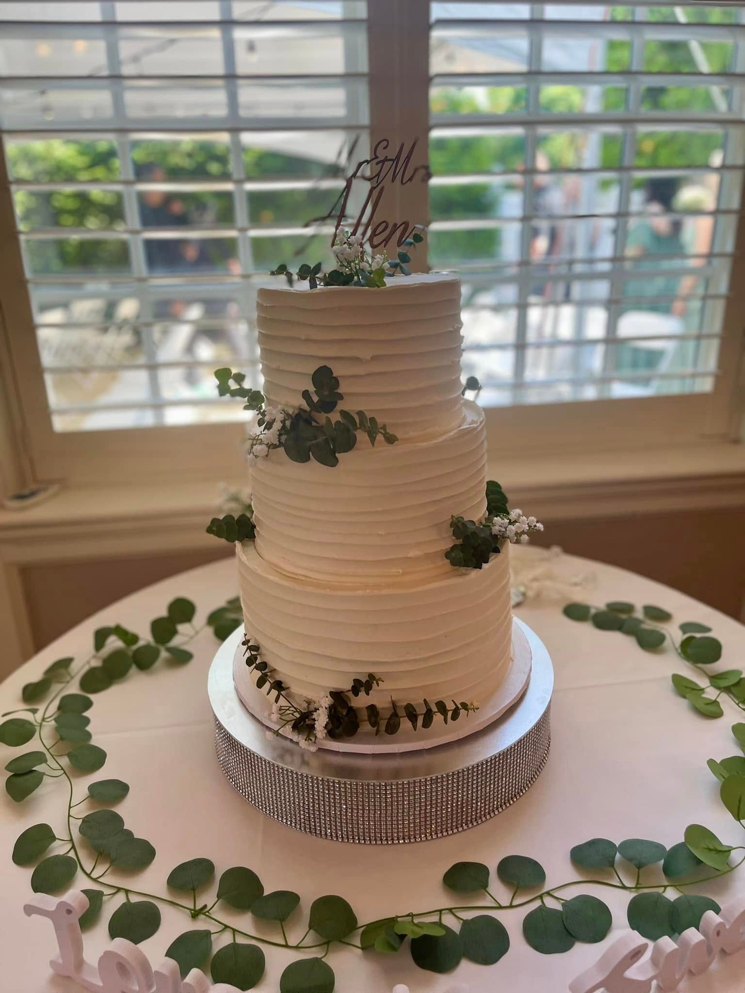 Three-tiered wedding cake with greenery and a 