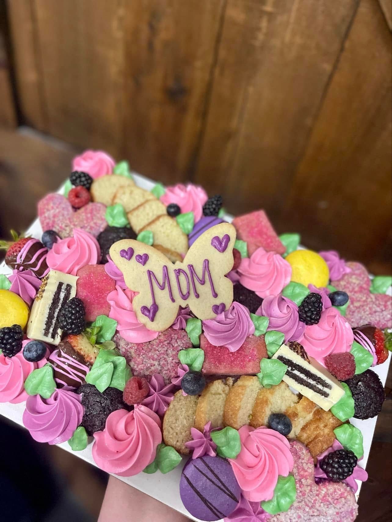 Mother's Day dessert board with pink frosting, cookies, berries, and a butterfly cookie that says 