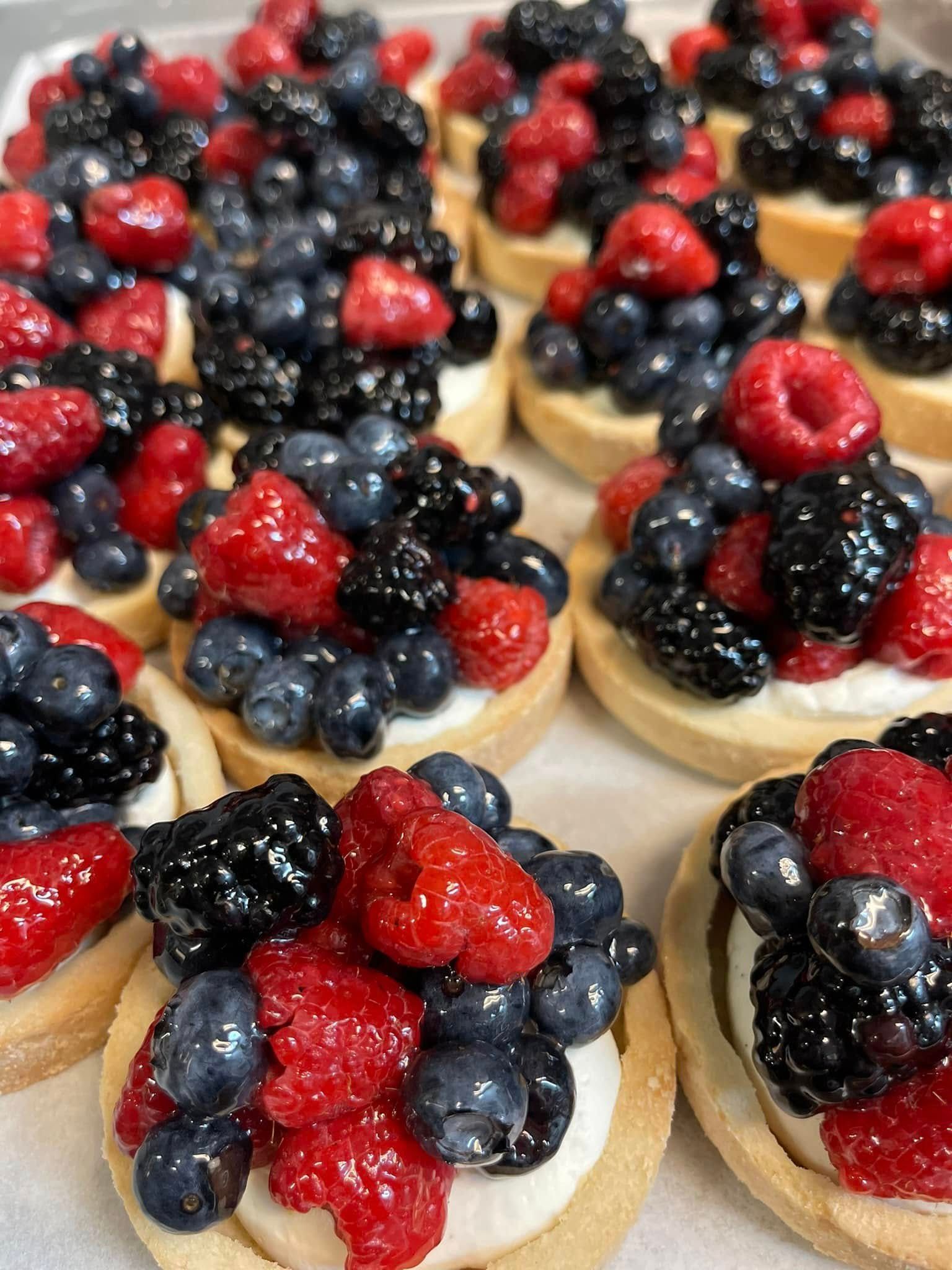 Mini fruit tarts topped with berries: blueberries, raspberries, and blackberries.