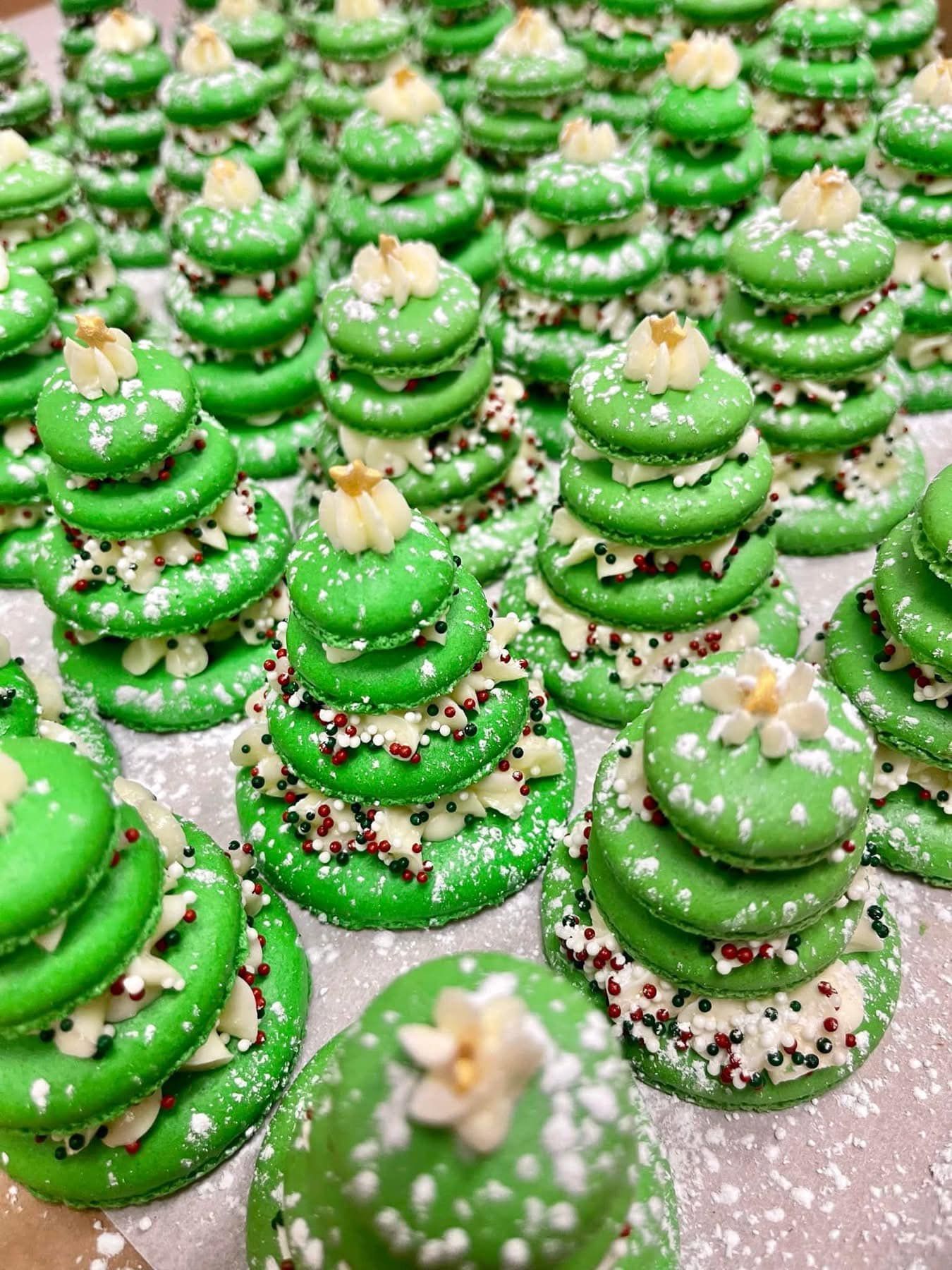 Green macaron Christmas trees with white sprinkles and nut decorations.