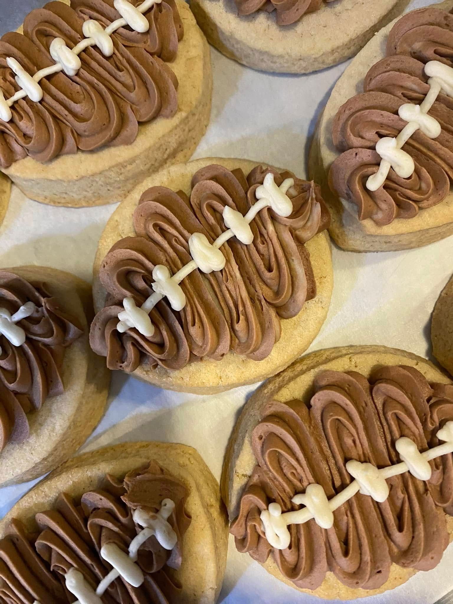 Close-up of frosted cookies. Brown football-shaped frosting on round cookies, with white icing laces.