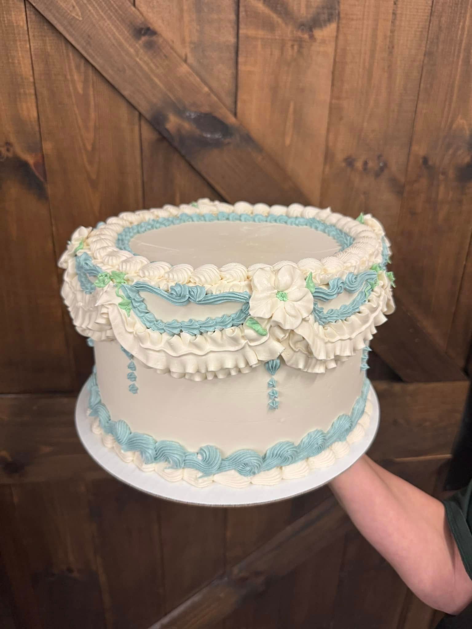 Cake with white and blue frosting, held against a wood background.