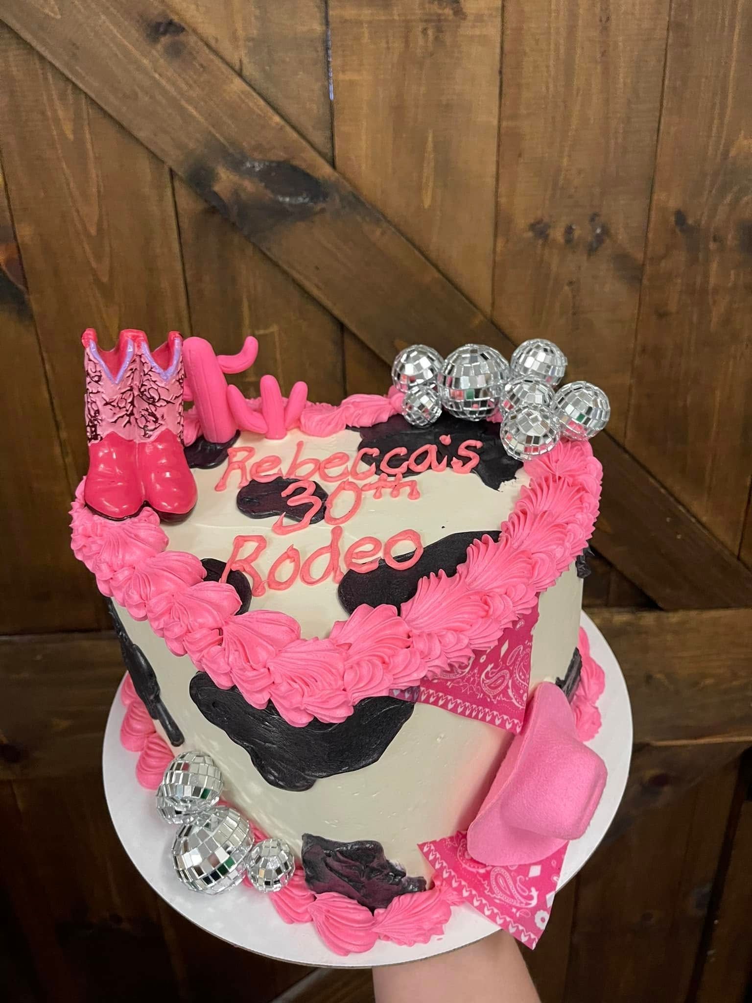 Heart-shaped cake with cow print frosting, pink accents, 