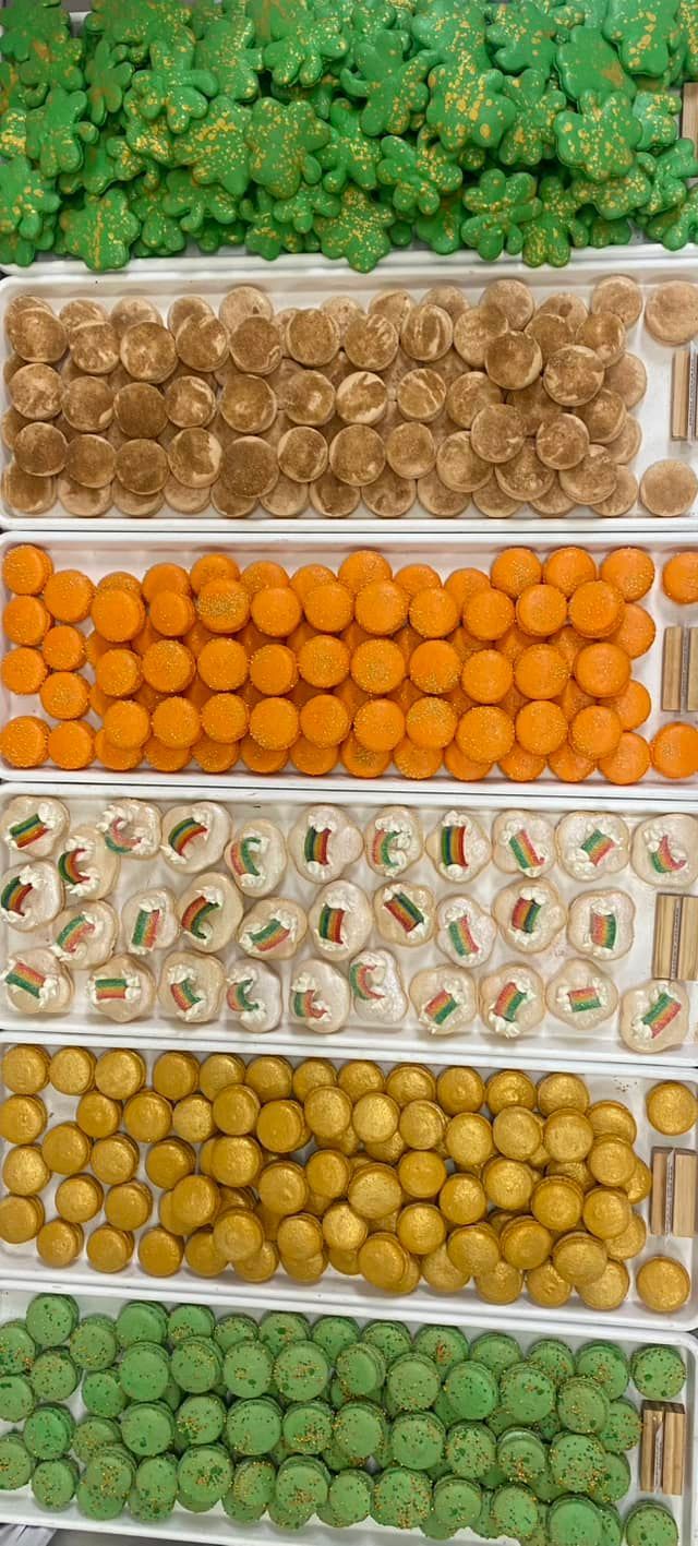 Rows of colorful candies: green clovers, brown, orange, white cookies, yellow, and green.