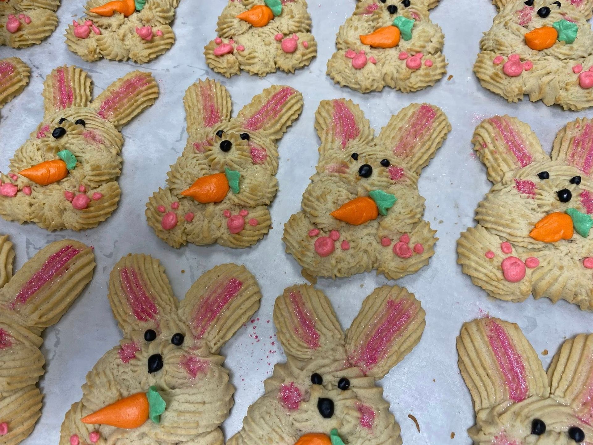 Easter bunny cookies decorated with pink ears, paws, carrot, and black eyes.