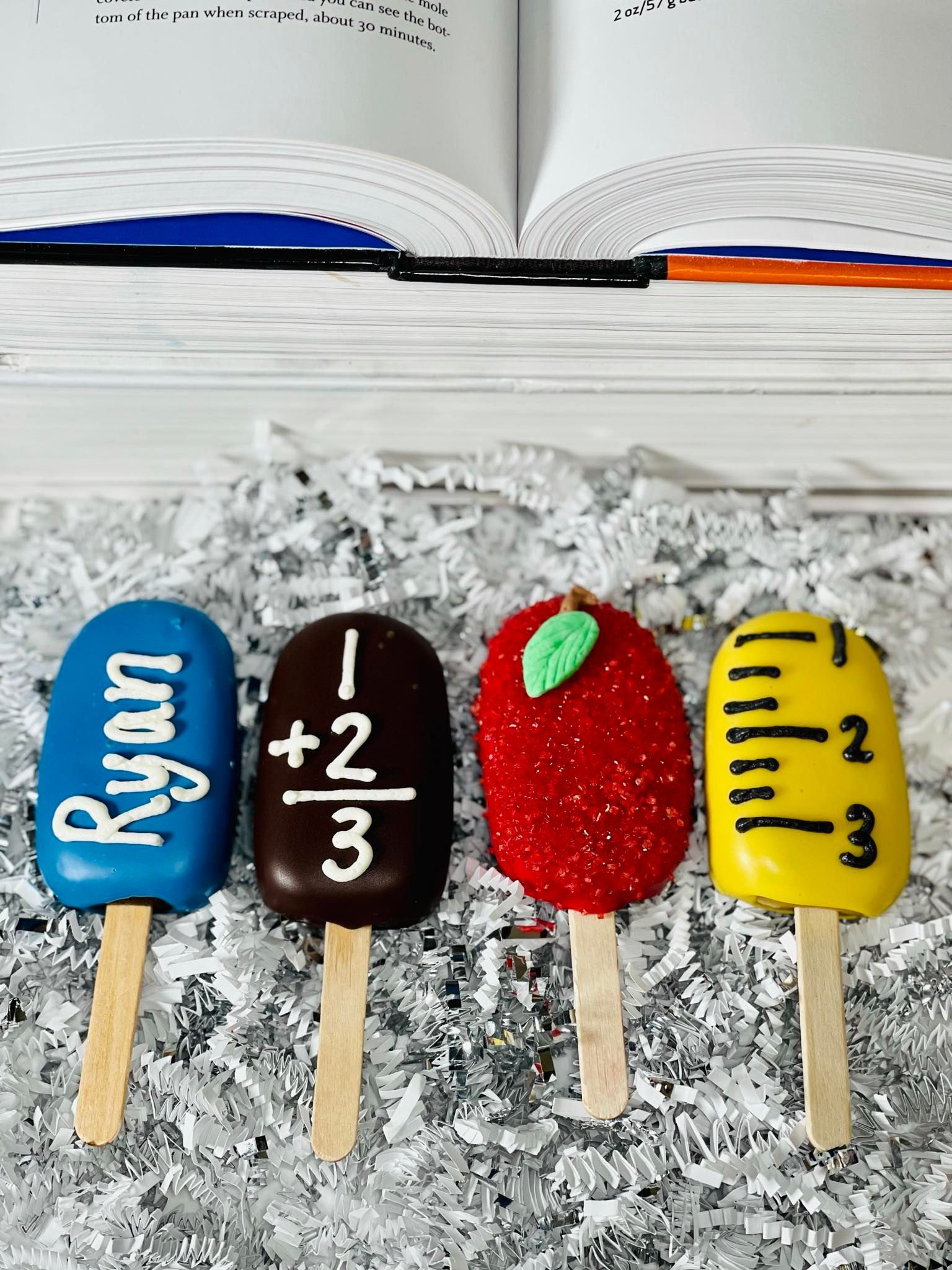 Four themed cake pops on sticks: blue with name 