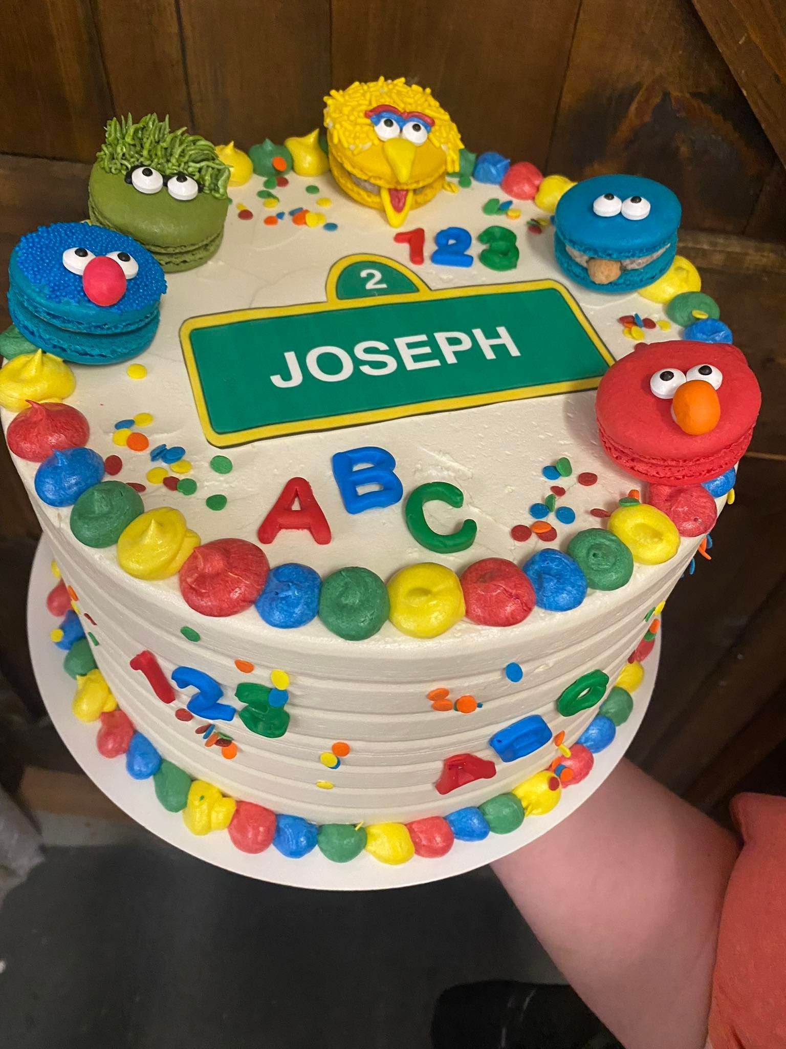 Sesame Street themed cake with character macarons, colorful frosting, and 