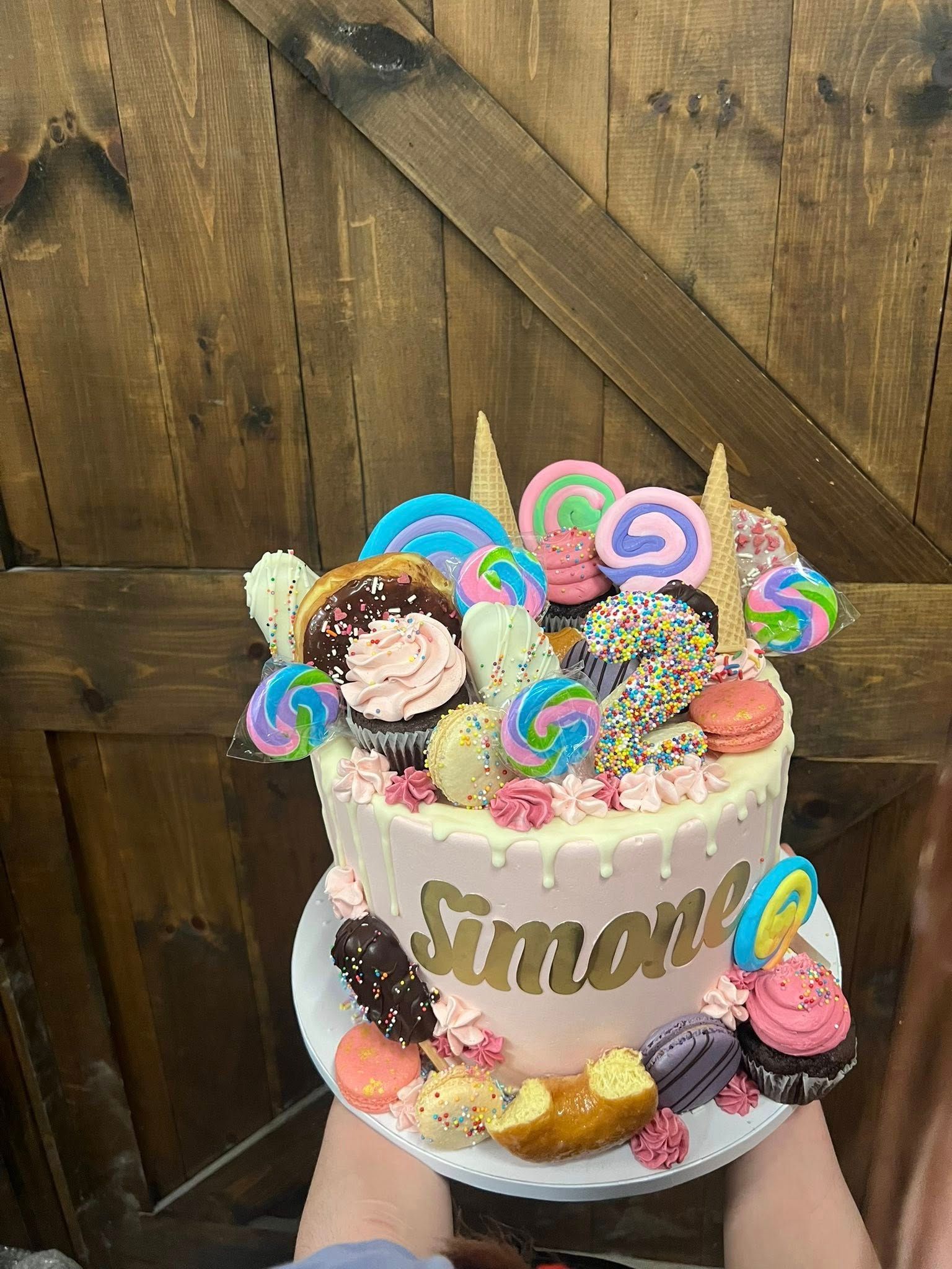 Pink cake decorated with candies, donuts, and macarons; 