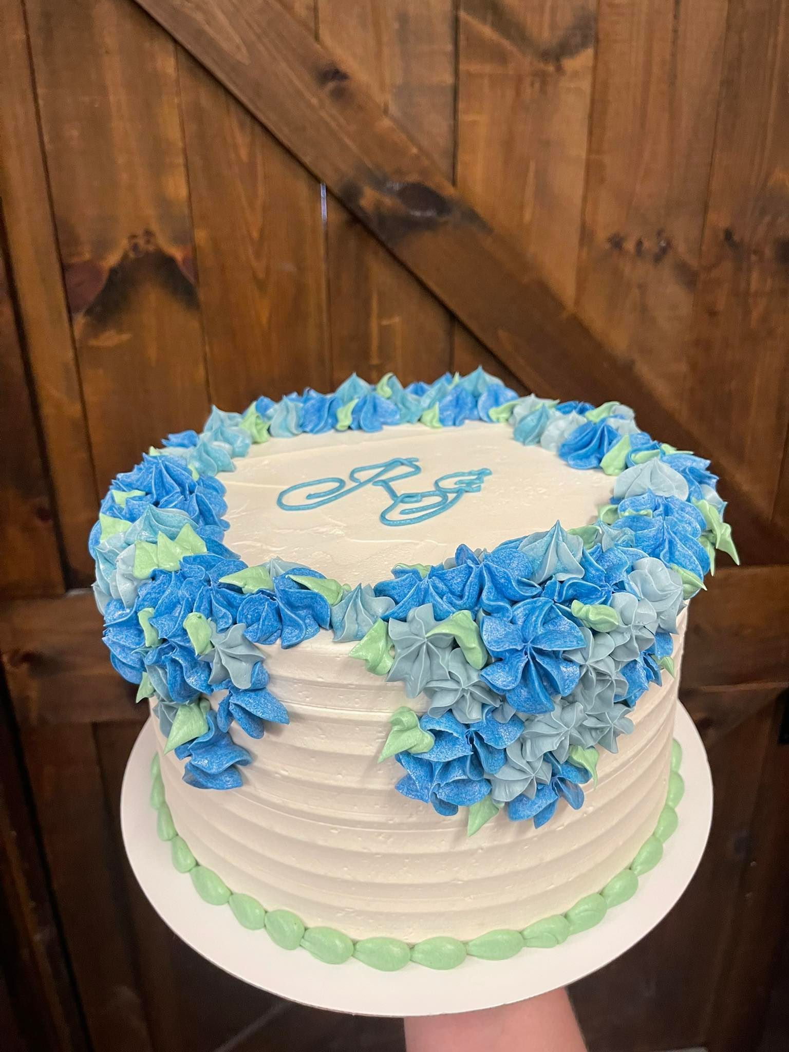 Cake with white frosting, blue and green floral design, and a light blue design on top.