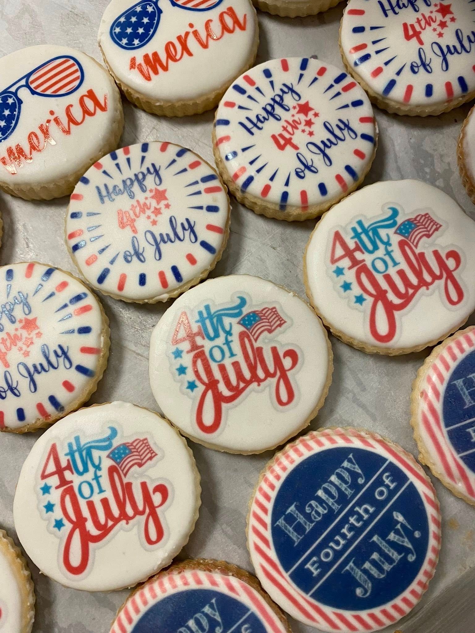 Close-up of Fourth of July cookies decorated with red, white, and blue designs and text.