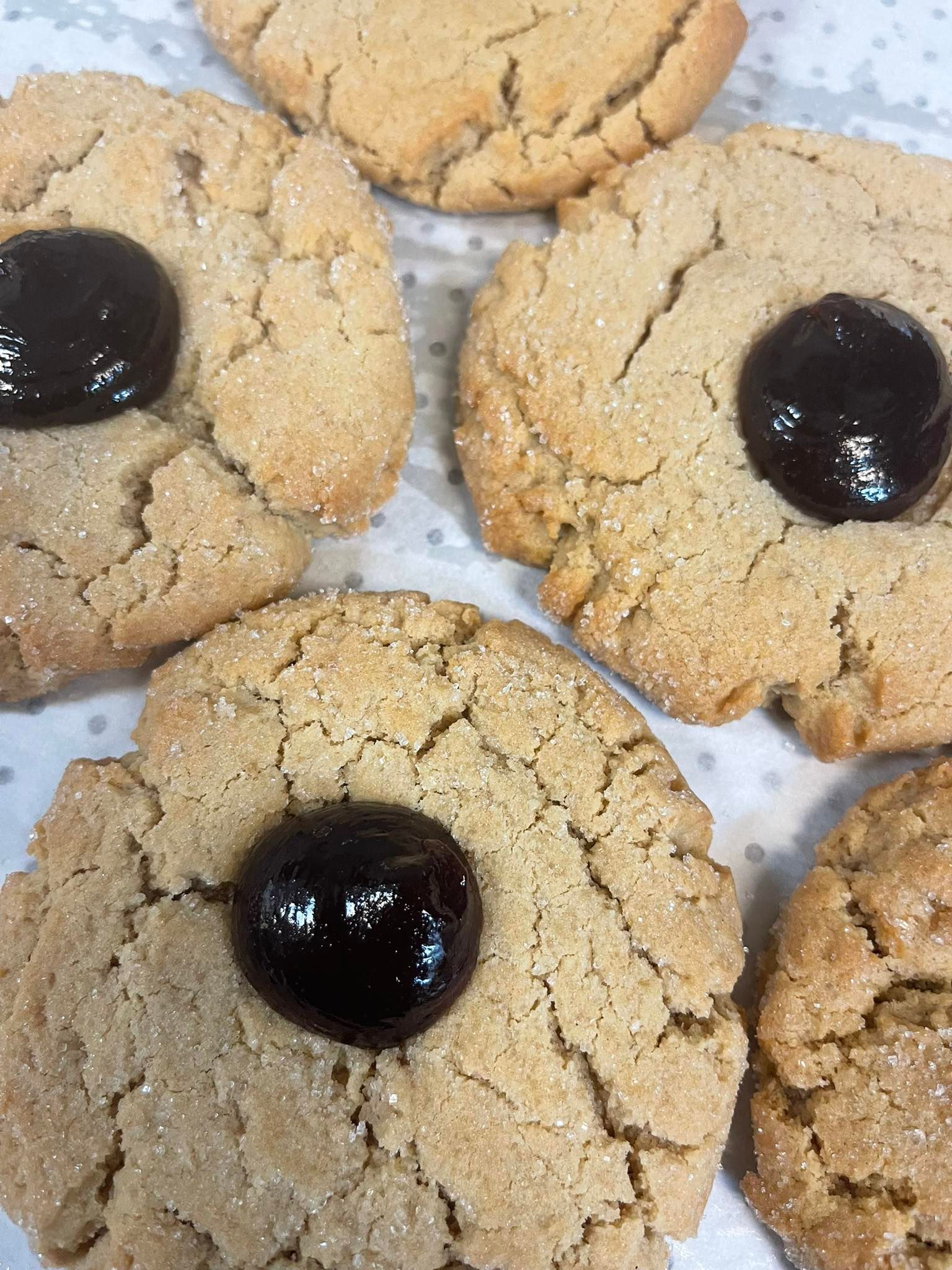 Peanut butter cookies, light brown with sugared edges, topped with dark chocolate centers.