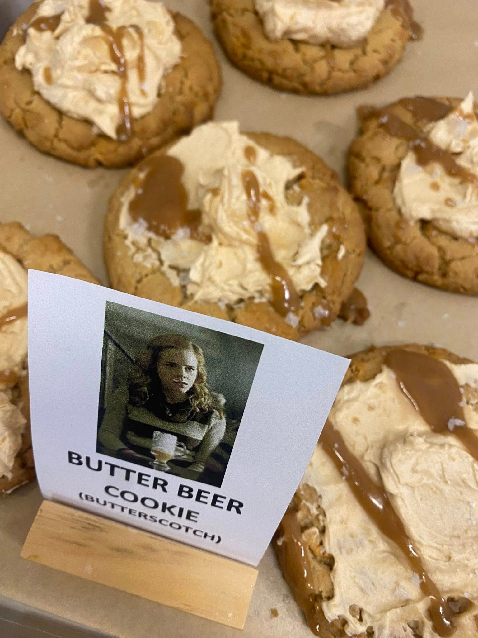 Butter beer cookies with caramel drizzle on a tray, with a sign showing a vintage photo and the words 