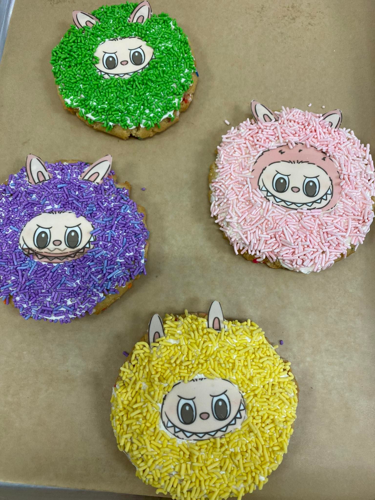 Four round cookies with a cartoon face and colorful sprinkles.