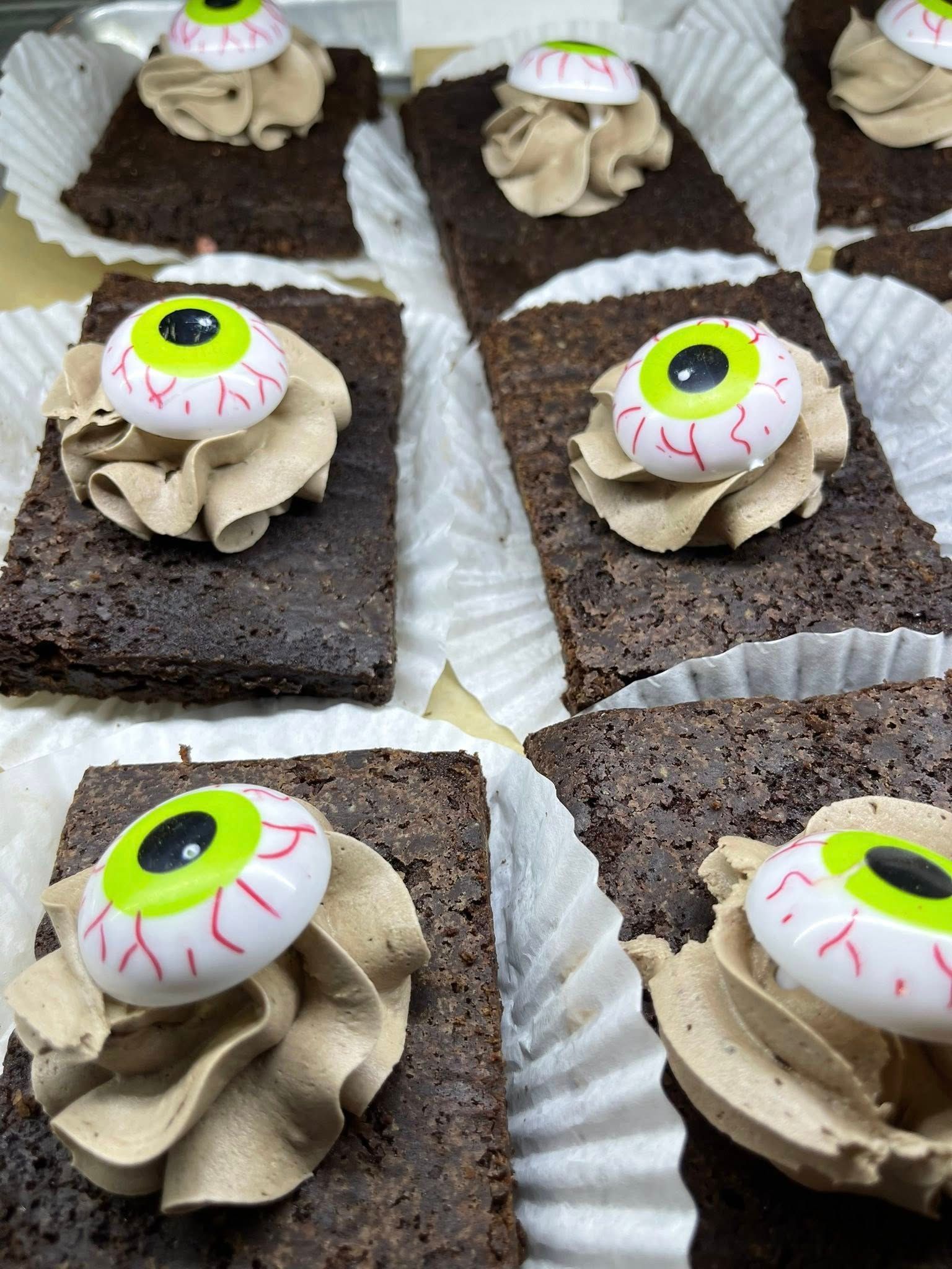 Brownies with tan frosting, topped with an eyeball candy.