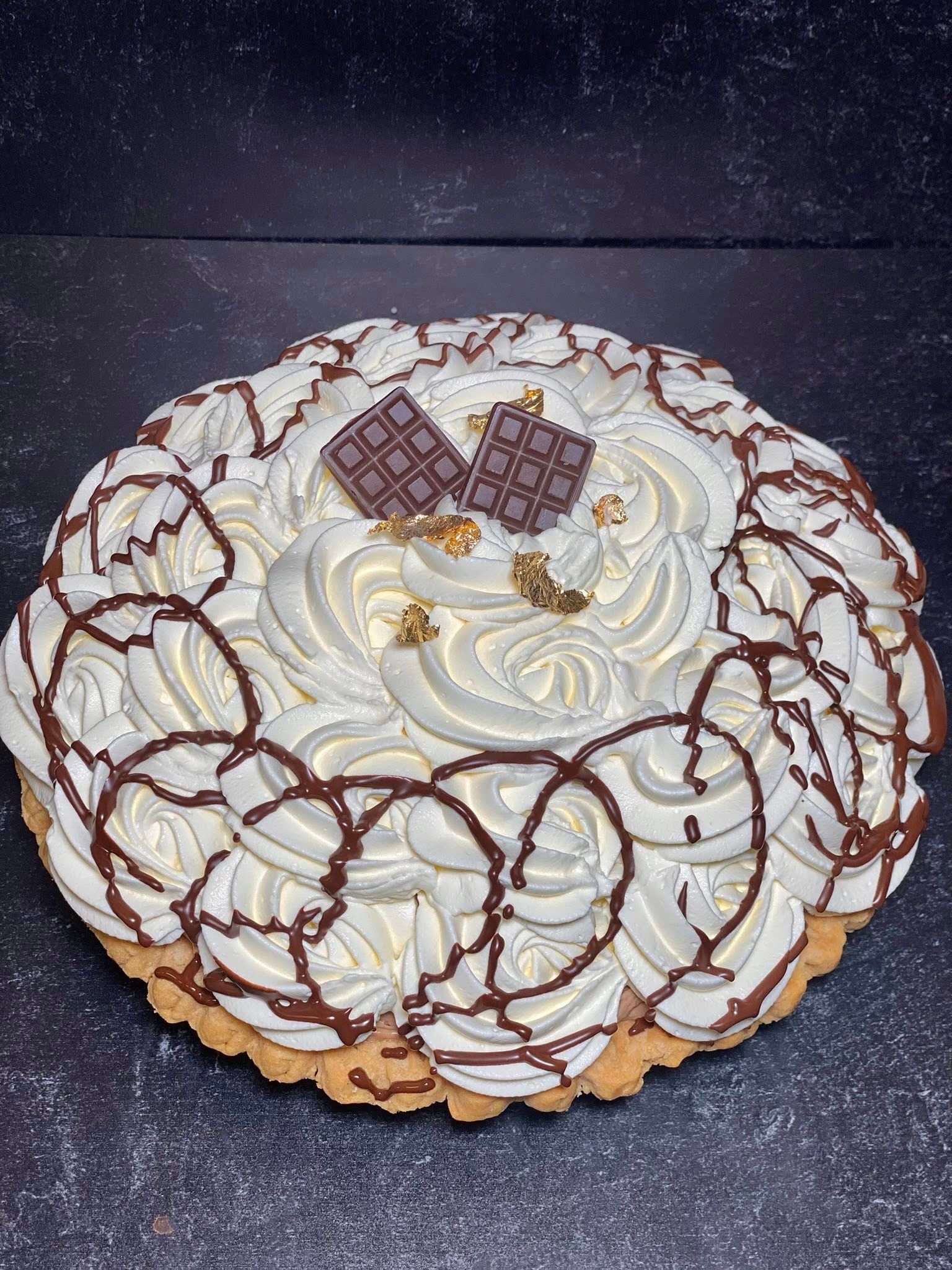 Chocolate cream tart with whipped cream swirls and chocolate squares.