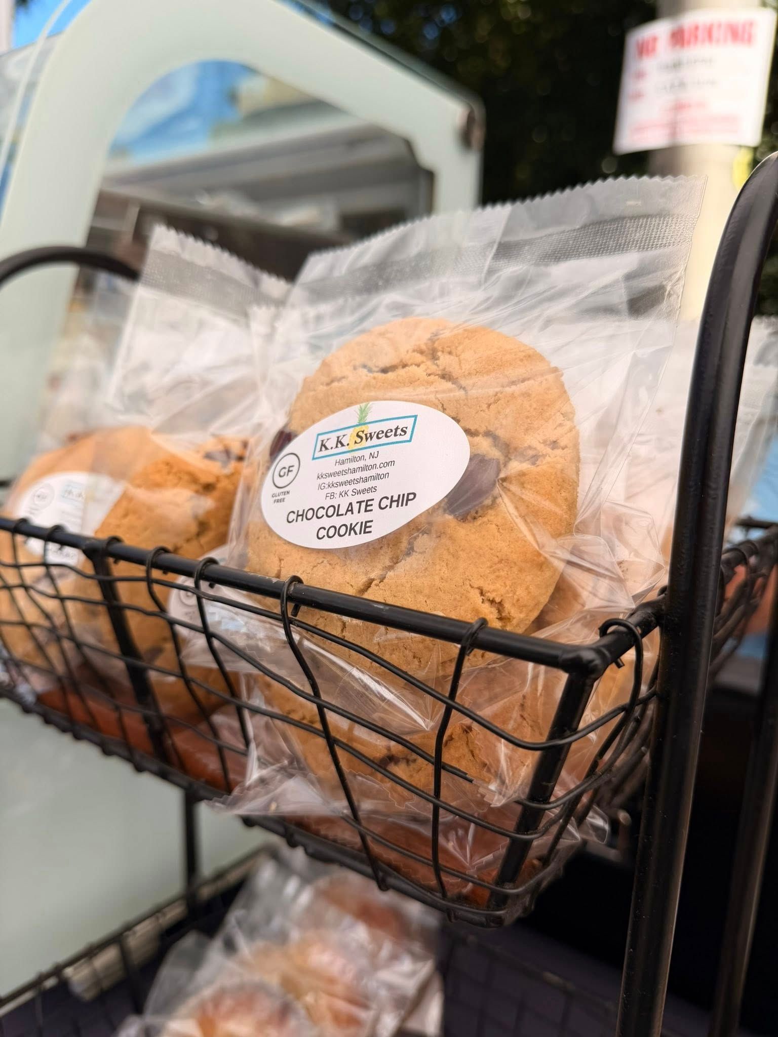 Cookies in clear plastic bags, displayed in a black wire basket at a market.