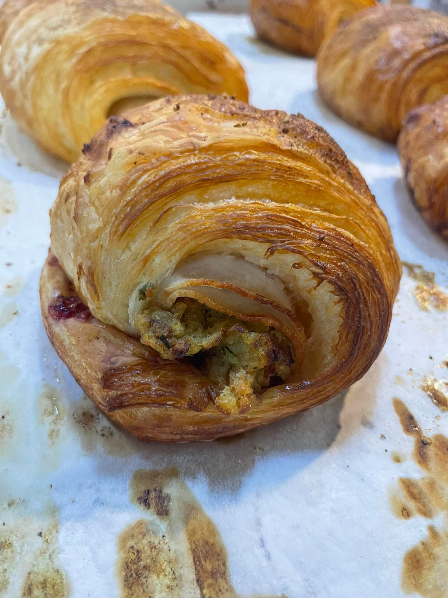 Flaky pastry with a green filling, on a baking sheet with other pastries.