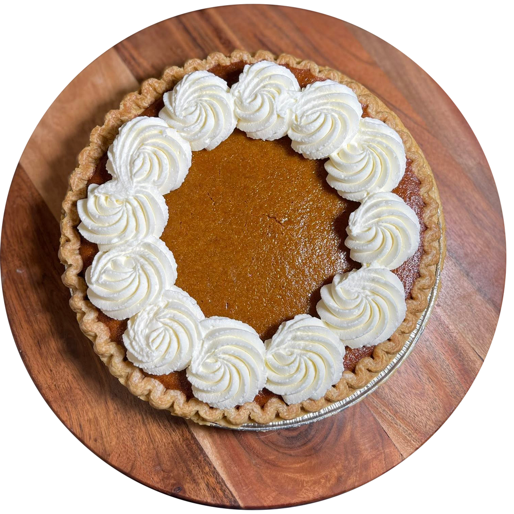 Pumpkin pie with whipped cream border on wooden board.