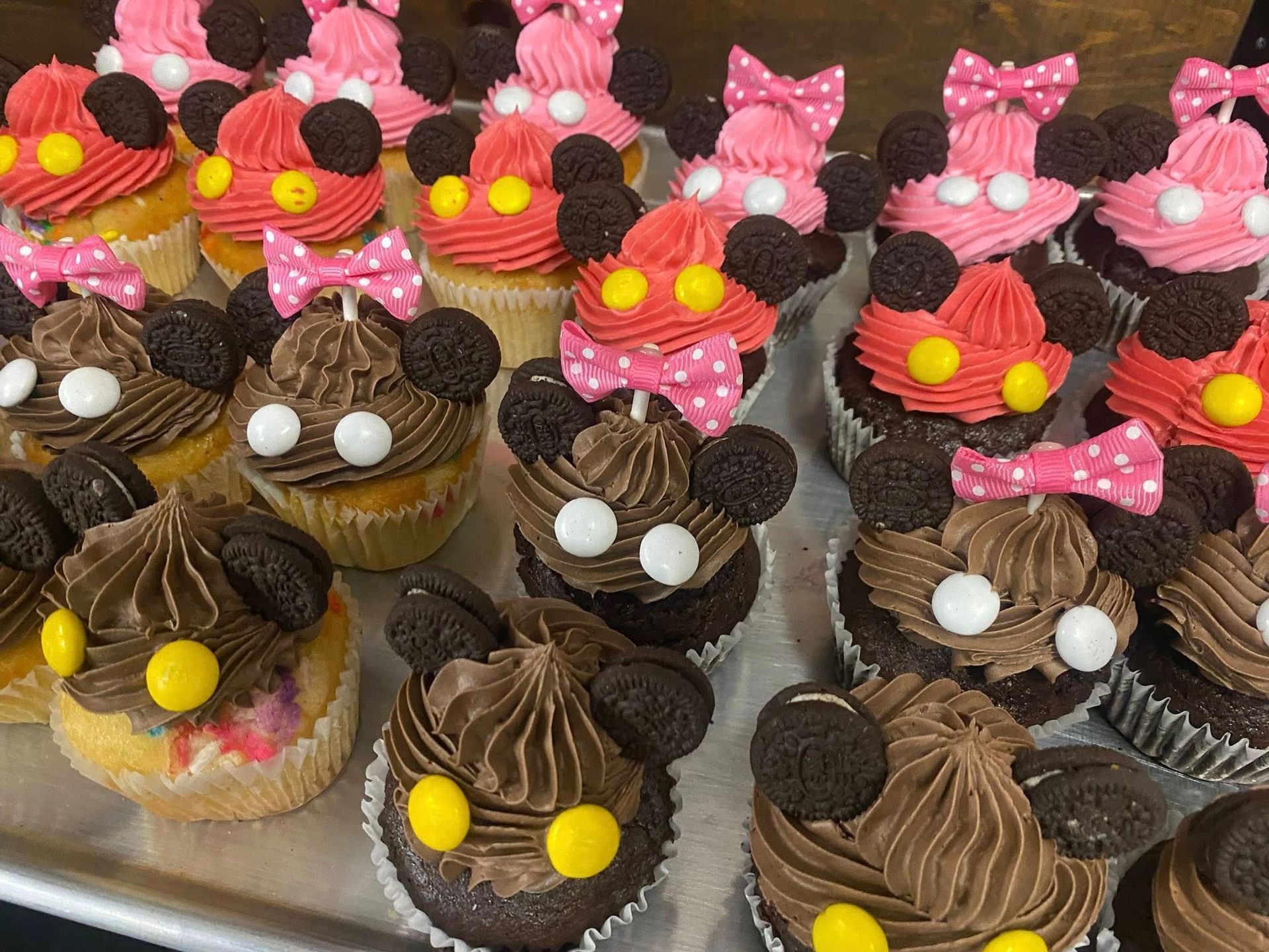 Cupcakes decorated as Mickey and Minnie Mouse; various colors, frosting, and bow details.