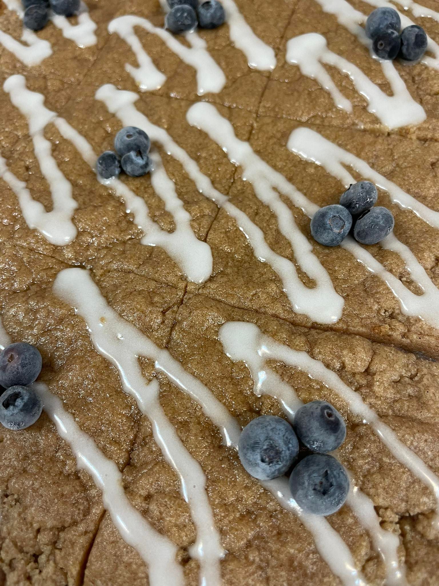 Brown dessert cake with white icing drizzle and blueberries.