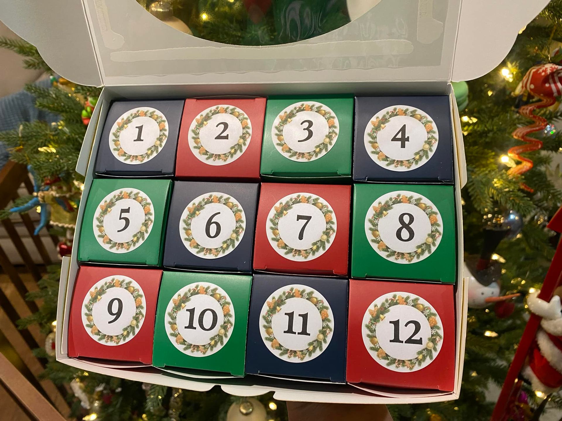 Advent calendar with twelve numbered boxes in a box. The boxes are green, red and navy blue with a wreath design.
