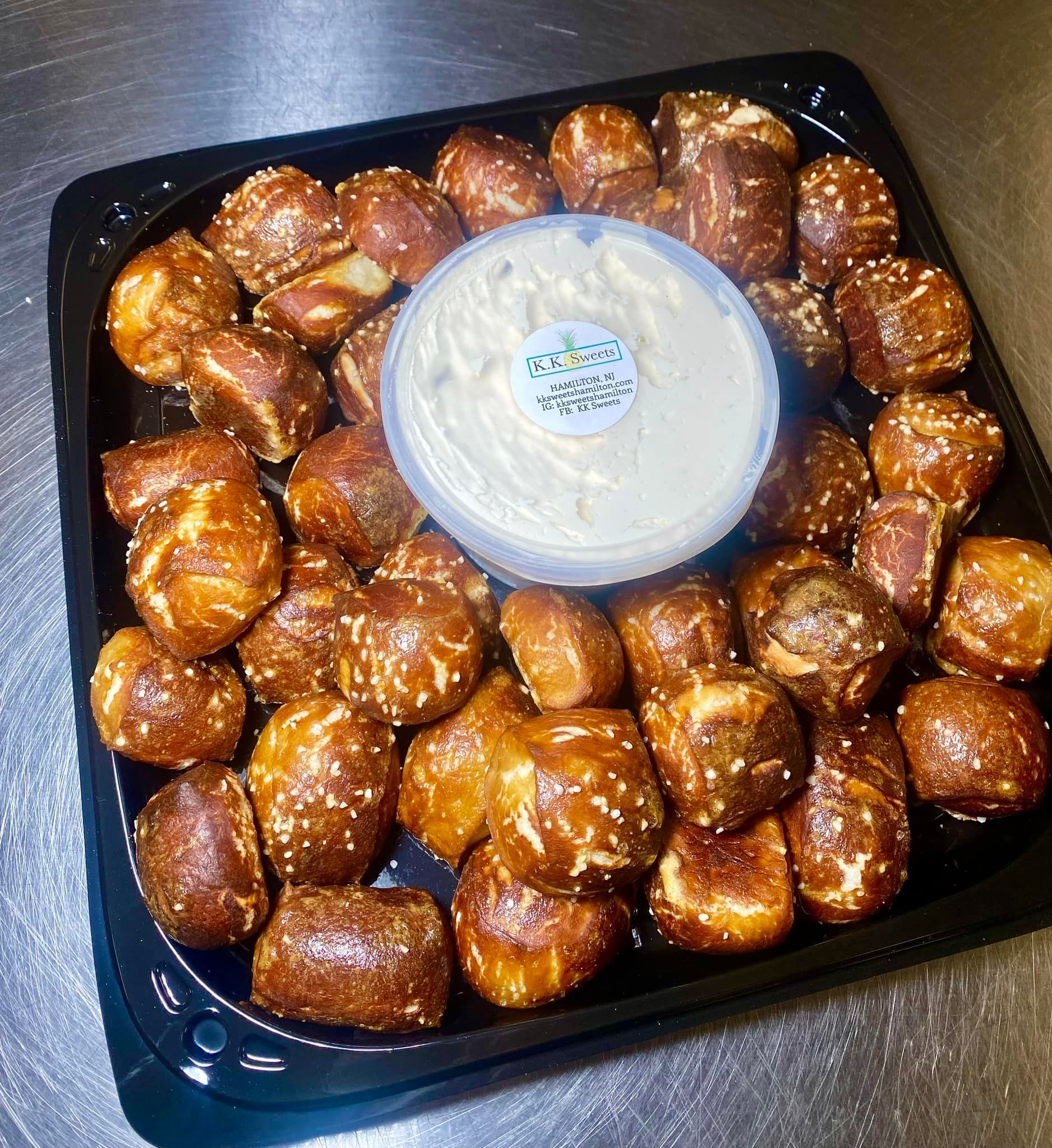 Pretzel bites on black tray with creamy dip.