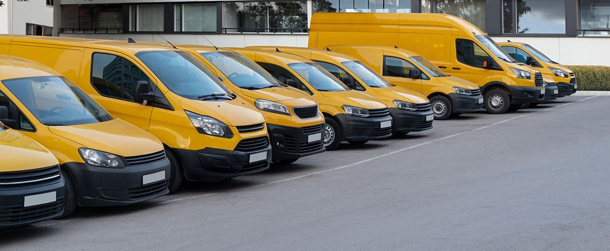 A row of yellow vans are parked in a parking lot.