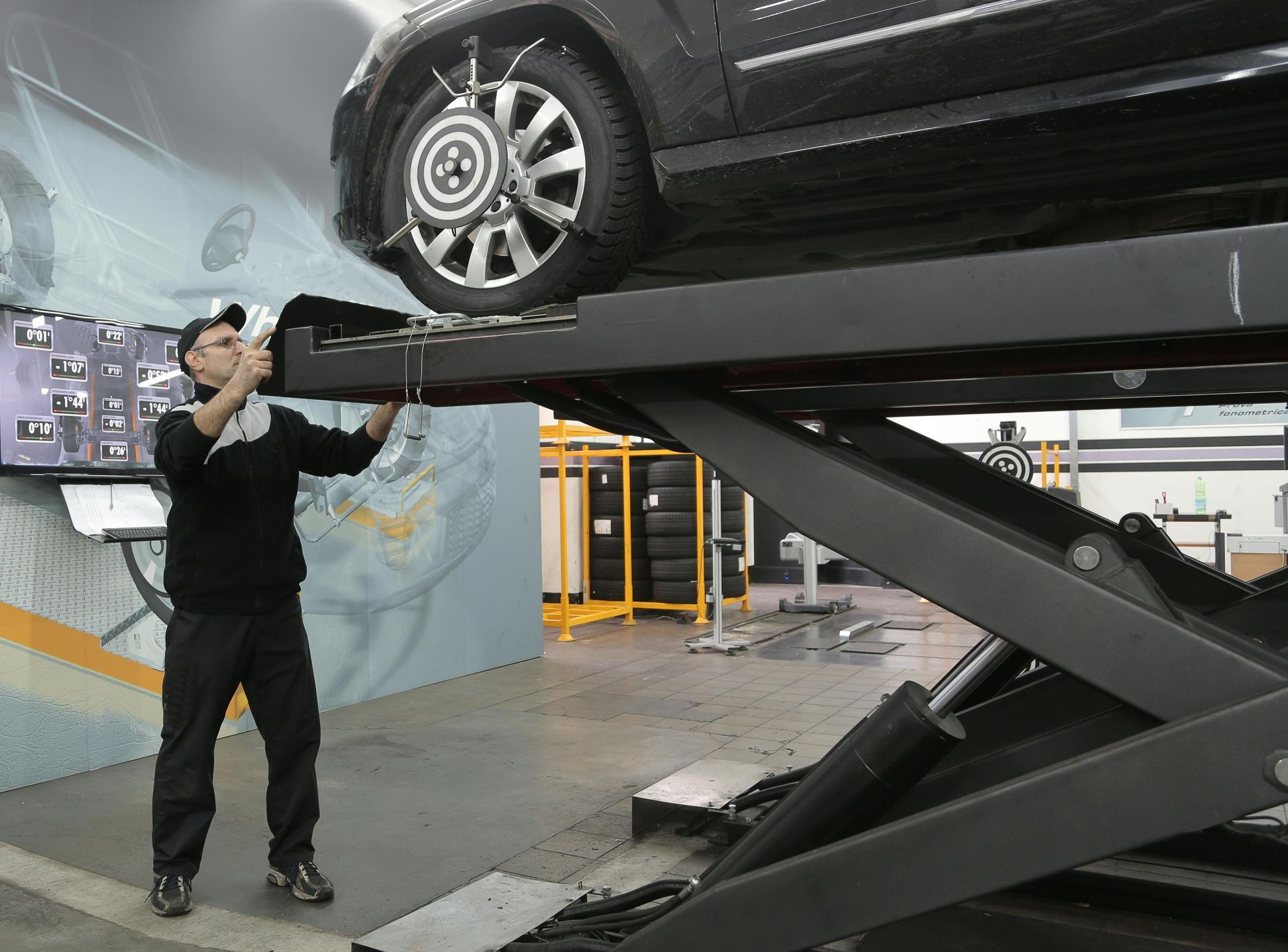 A man is working on a car on a lift in a garage.