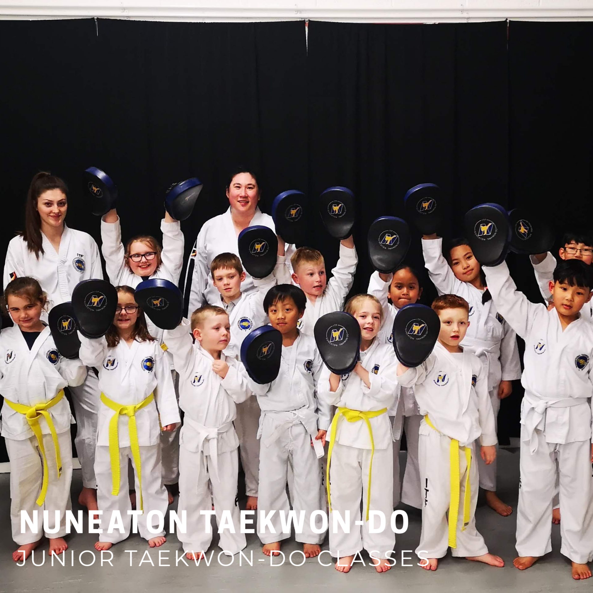 Children in martial arts class holding pads up