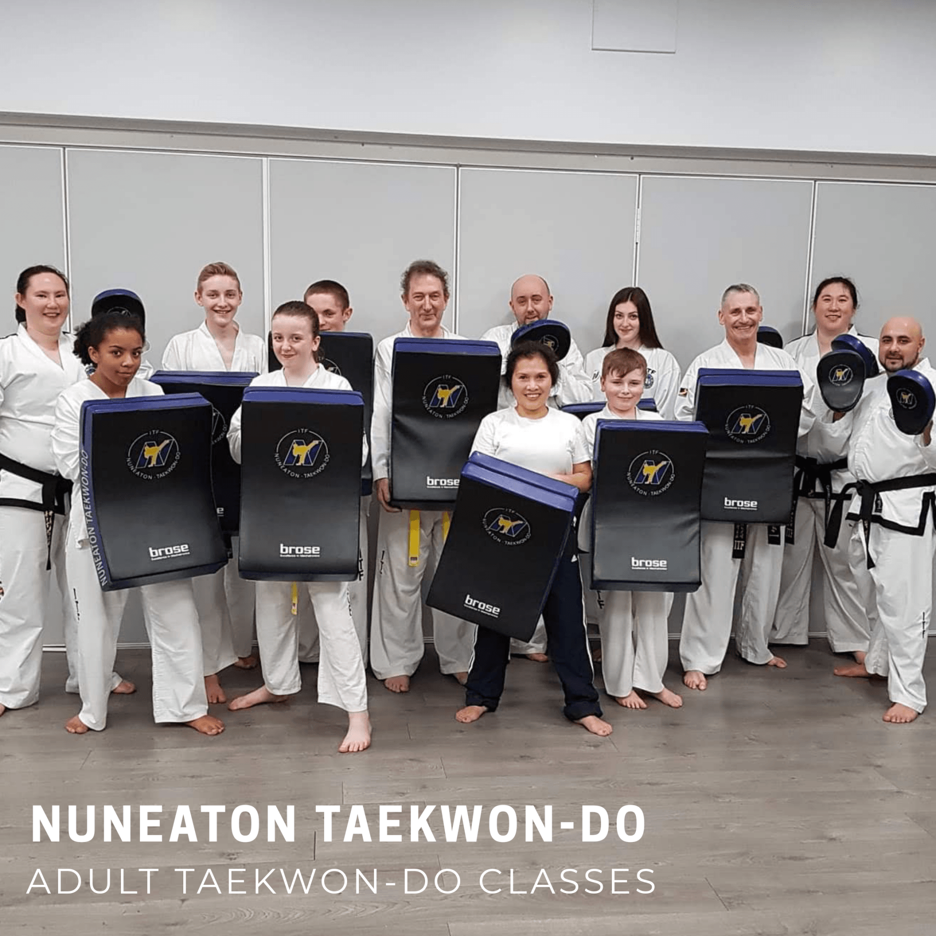 Adults in martial arts class holding pads up