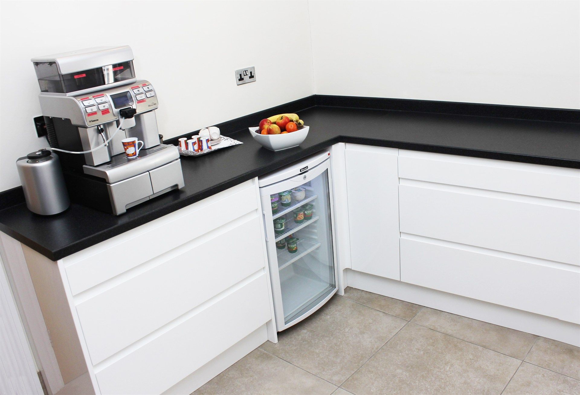 A kitchen with white cabinets and black counter tops