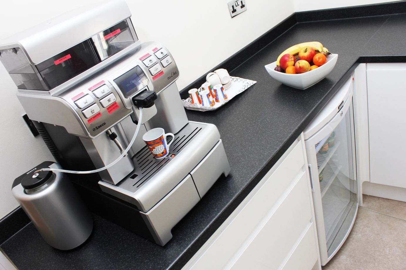 A kitchen counter with a coffee maker and a bowl of fruit