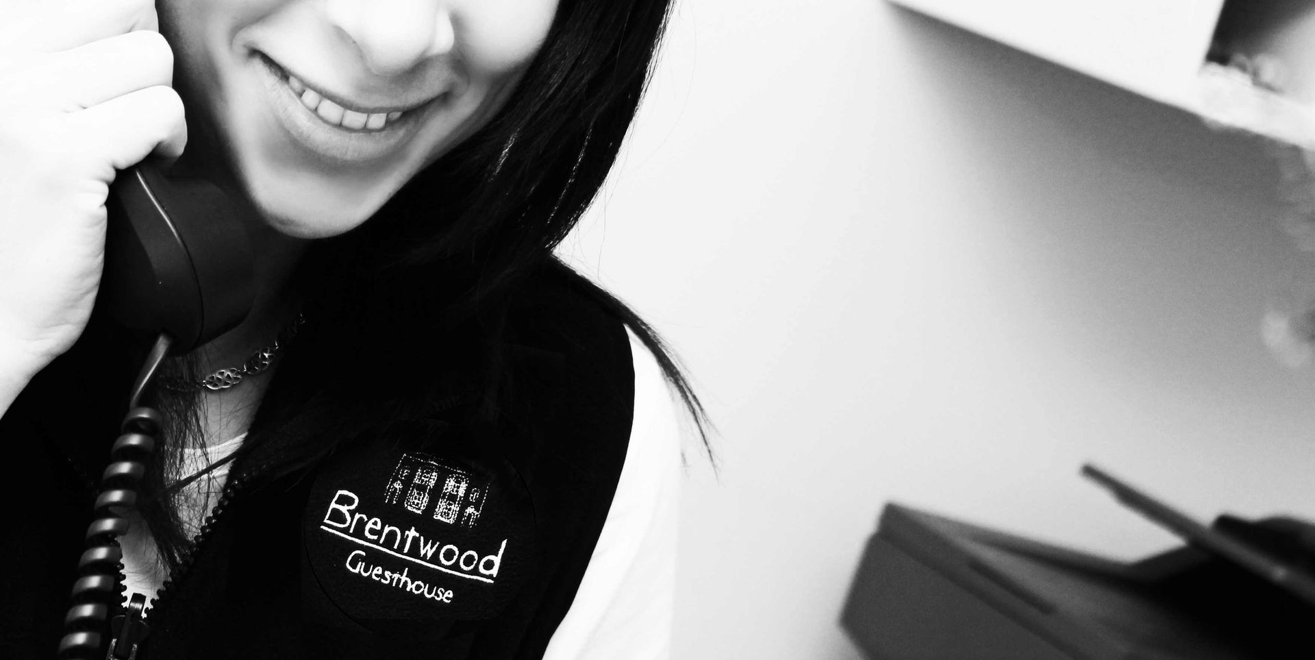 A woman is smiling while talking on a phone.