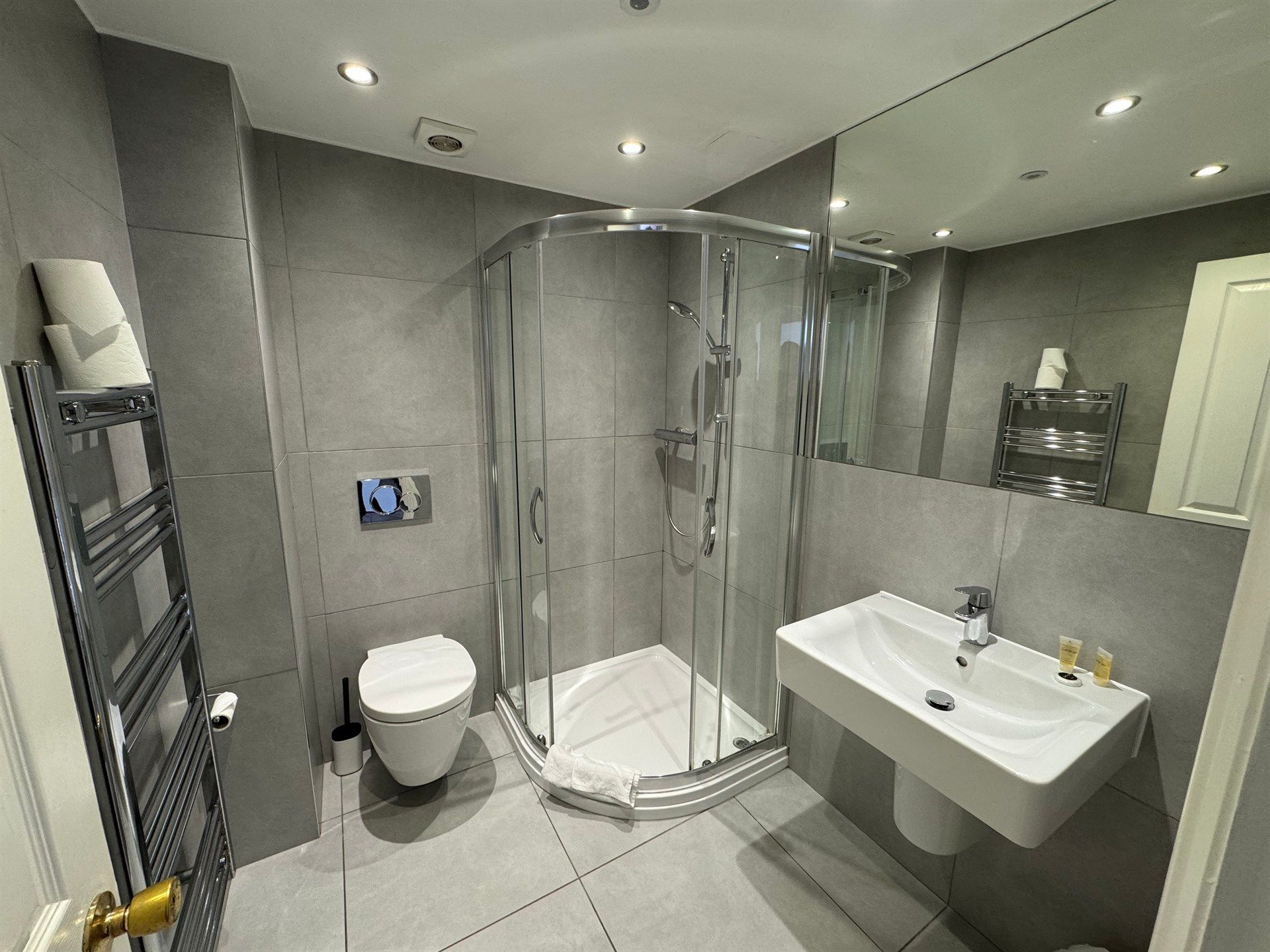 A bathroom with a toilet , sink , shower and mirror.