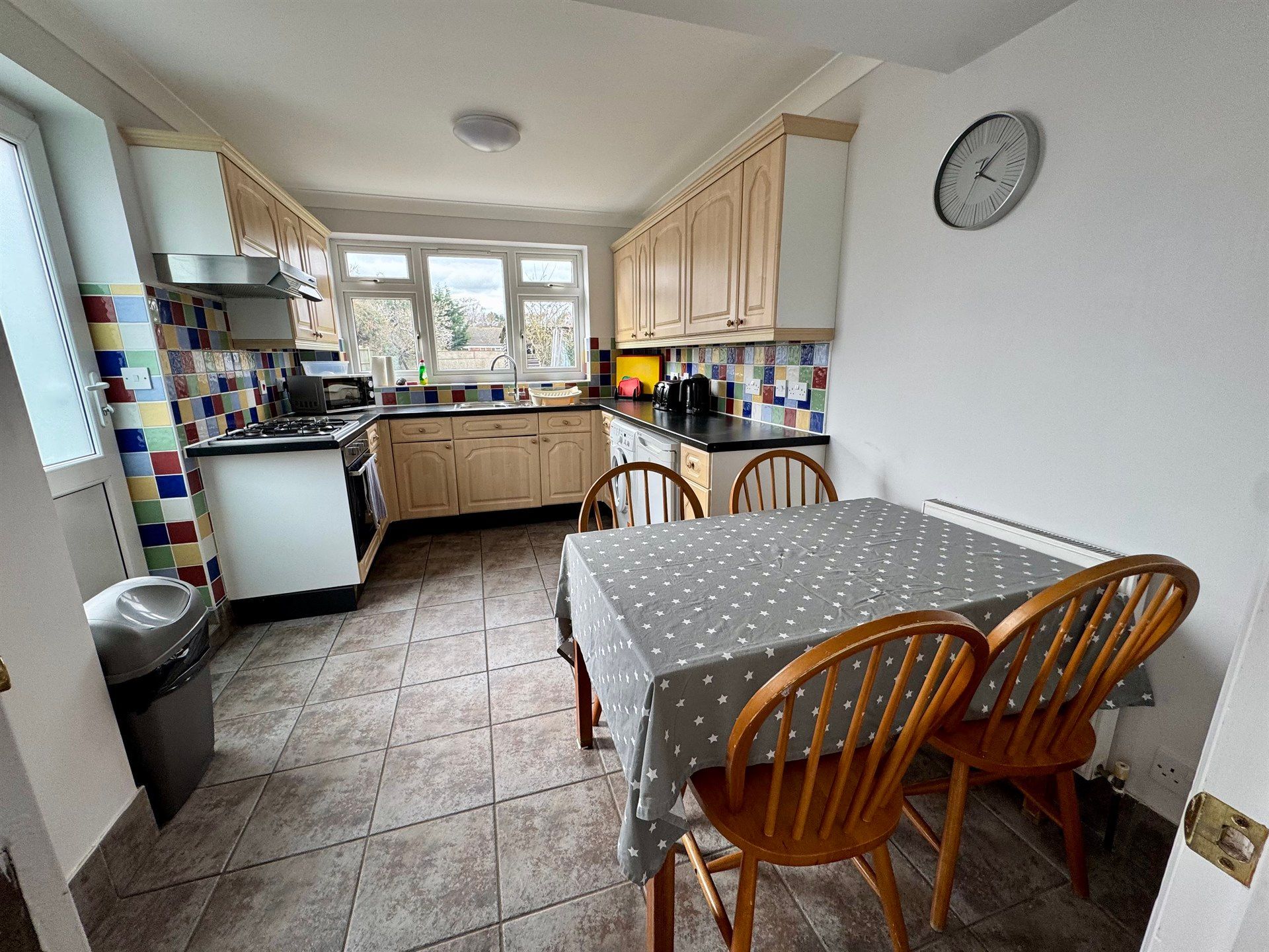 A kitchen with a table and chairs and a clock on the wall.