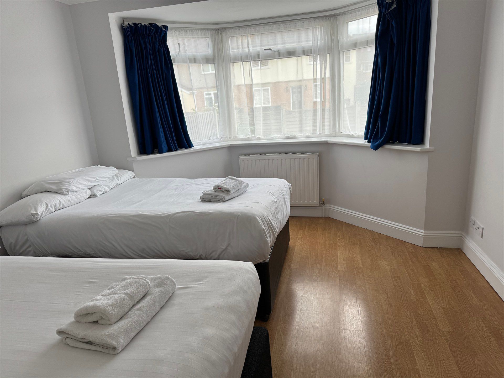 A bedroom with two beds and a large window.